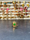 Bague dorée à motif ovale texturé et détail vert